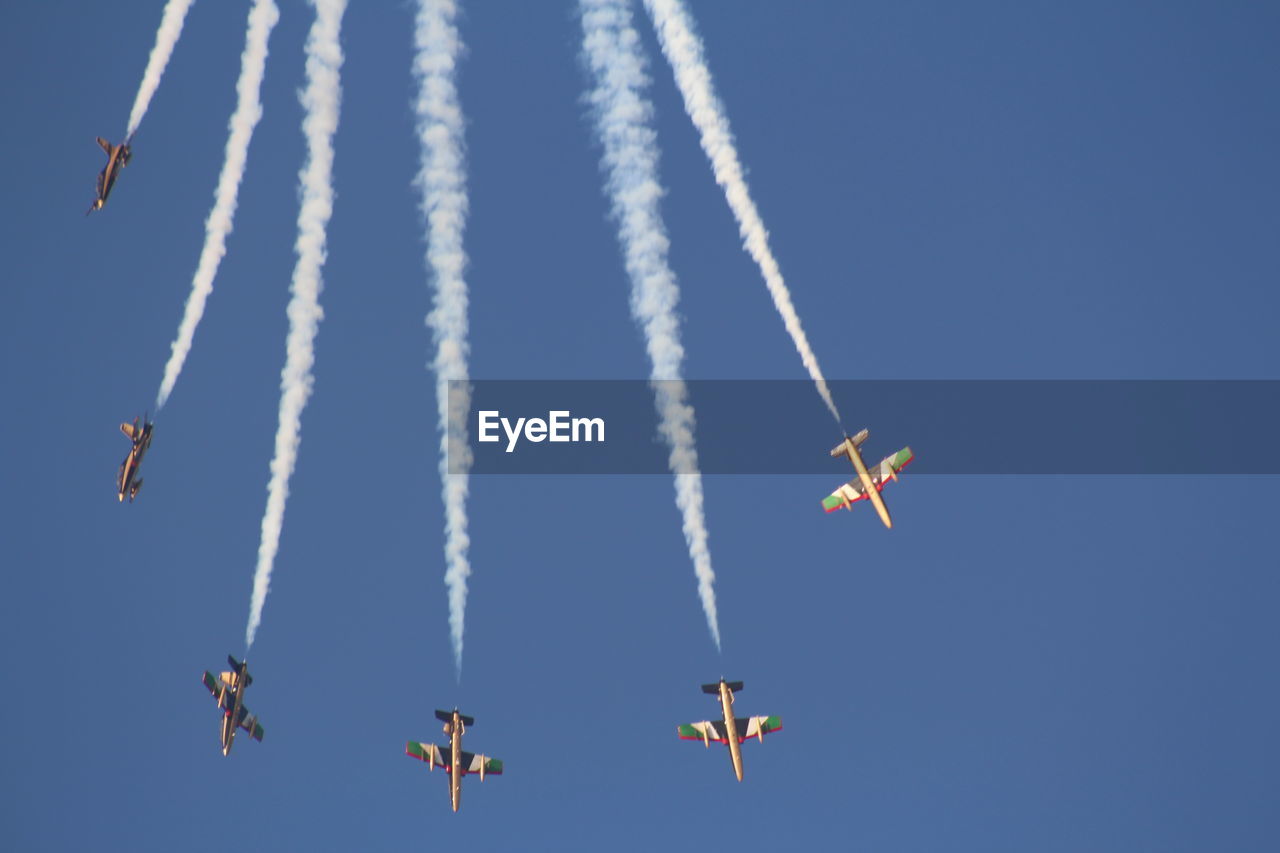 Low angle view of airshow against clear blue sky