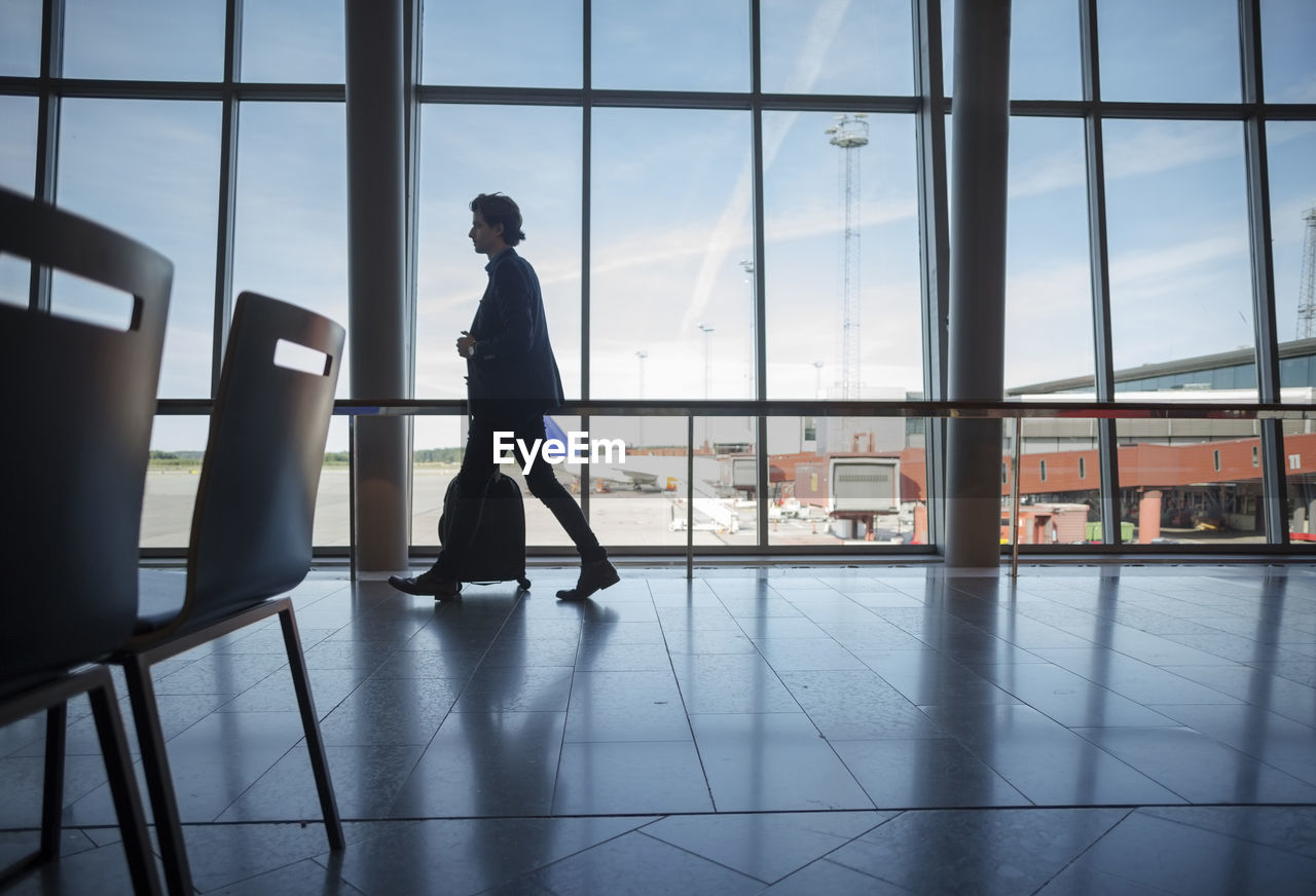 Side view of businessman walking with luggage at airport