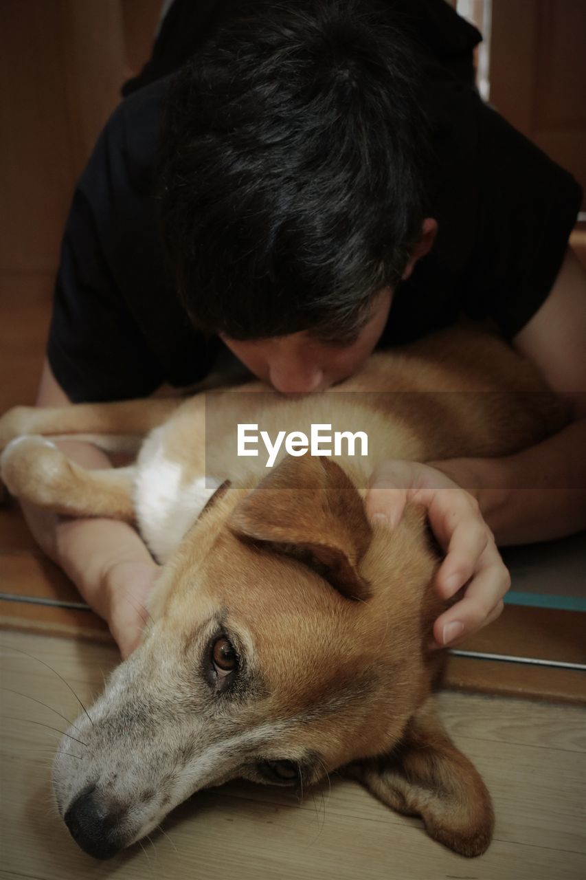 Teenage boy cuddling dog