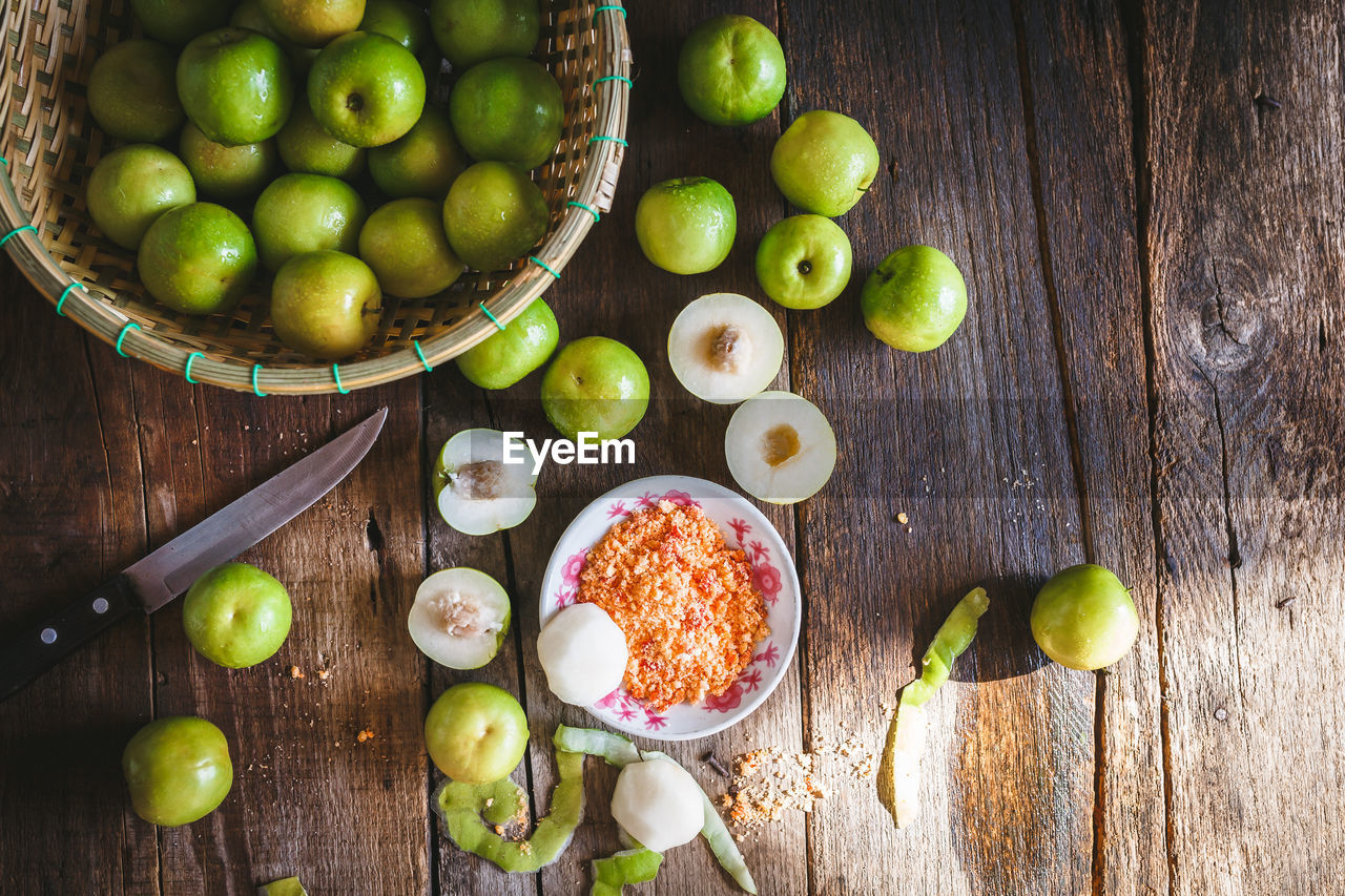 Directly above shot of granny smith apple and knife with basket on table