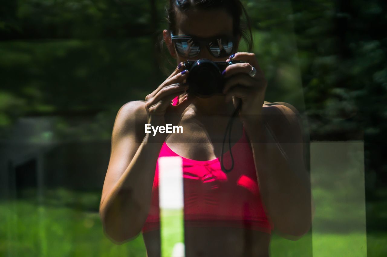 MIDSECTION OF MAN PHOTOGRAPHING IN PINK CAMERA