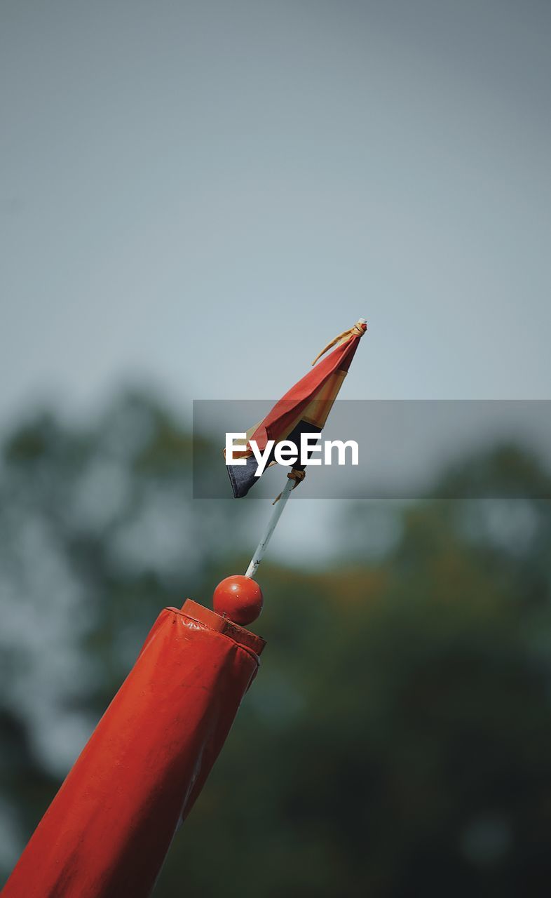 CLOSE-UP OF RED TOY ON GRASS AGAINST SKY