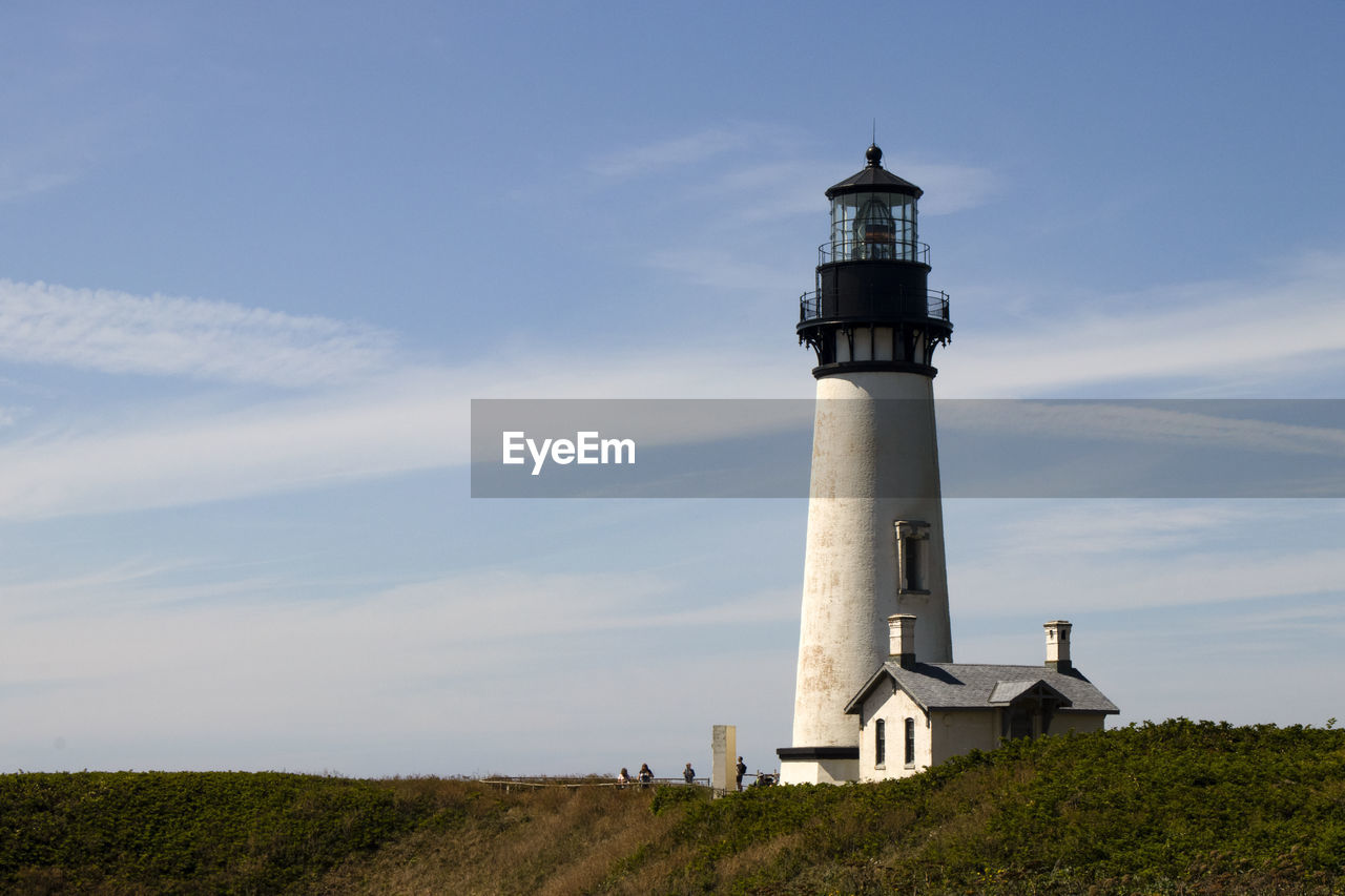 Lighthouse by building against sky