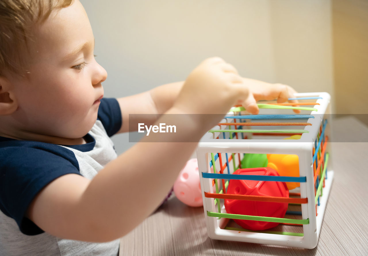 A cute toddler boy is playing a game with sensory colorful balls. sensory and tactile activities.