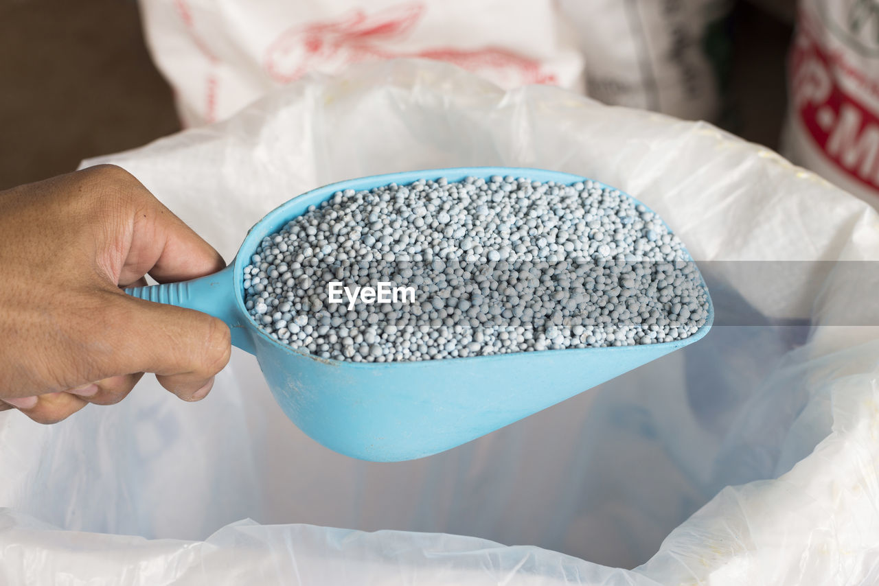 Close-up of hand holding fertilizer in spatula