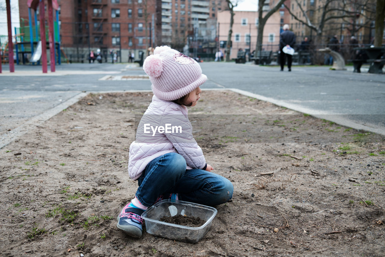 Girl digging in the dirt on the playground on a foggy fall day