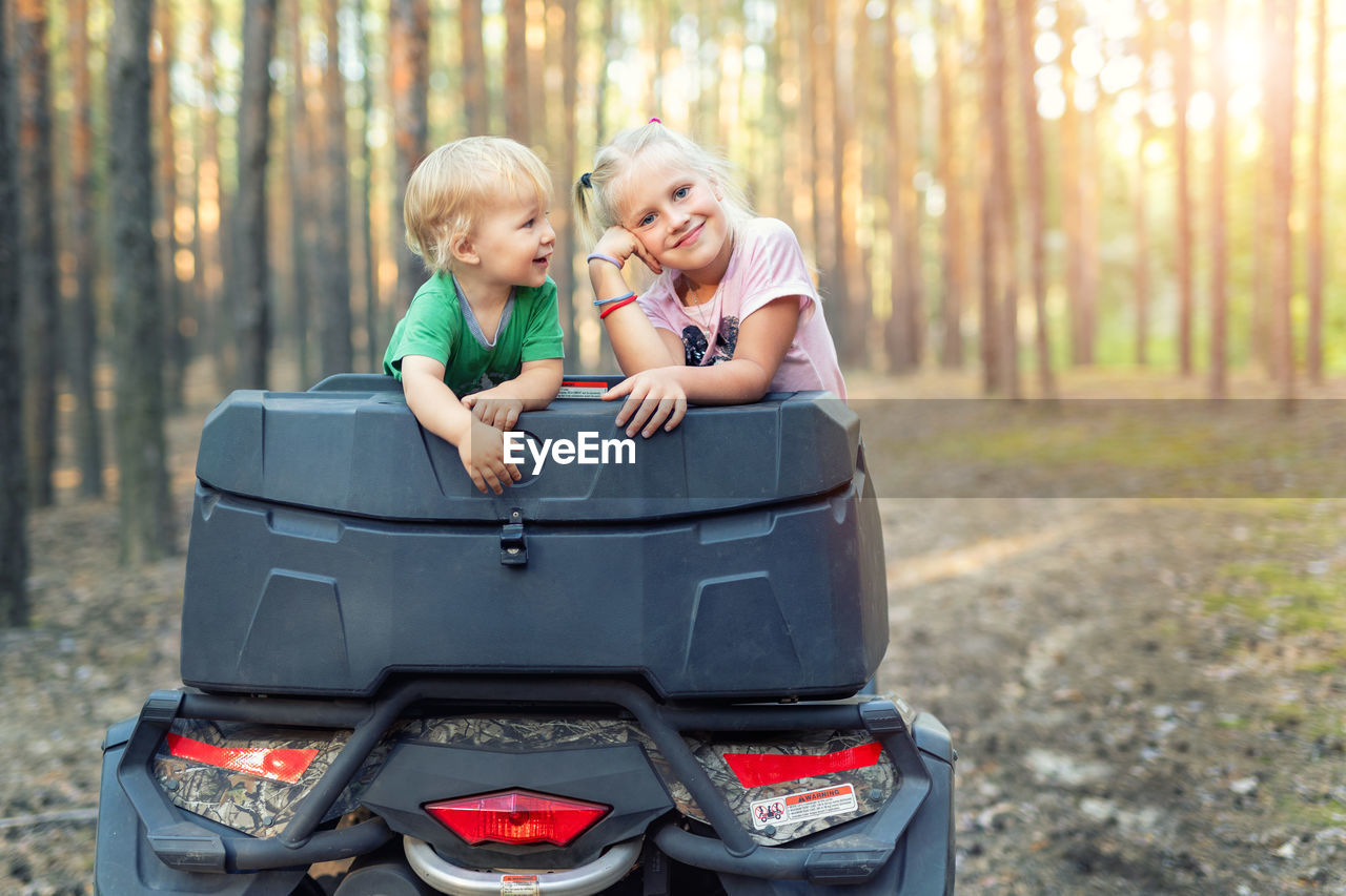 Girl with brother in quadbike at forest