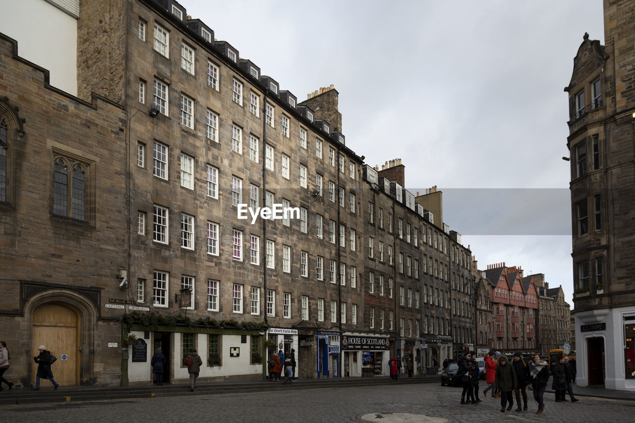 PEOPLE WALKING ON STREET BY BUILDINGS IN CITY