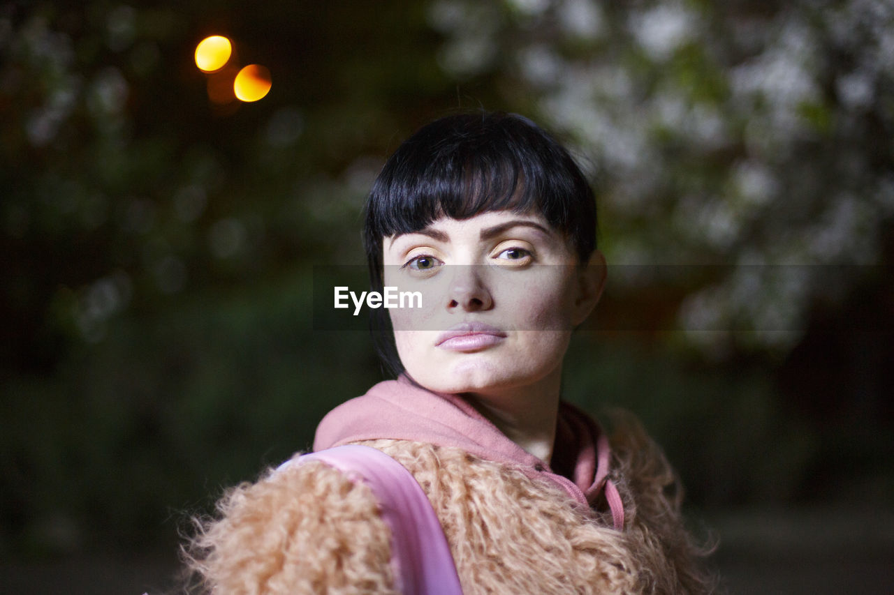 Portrait of woman wearing fur coat against trees