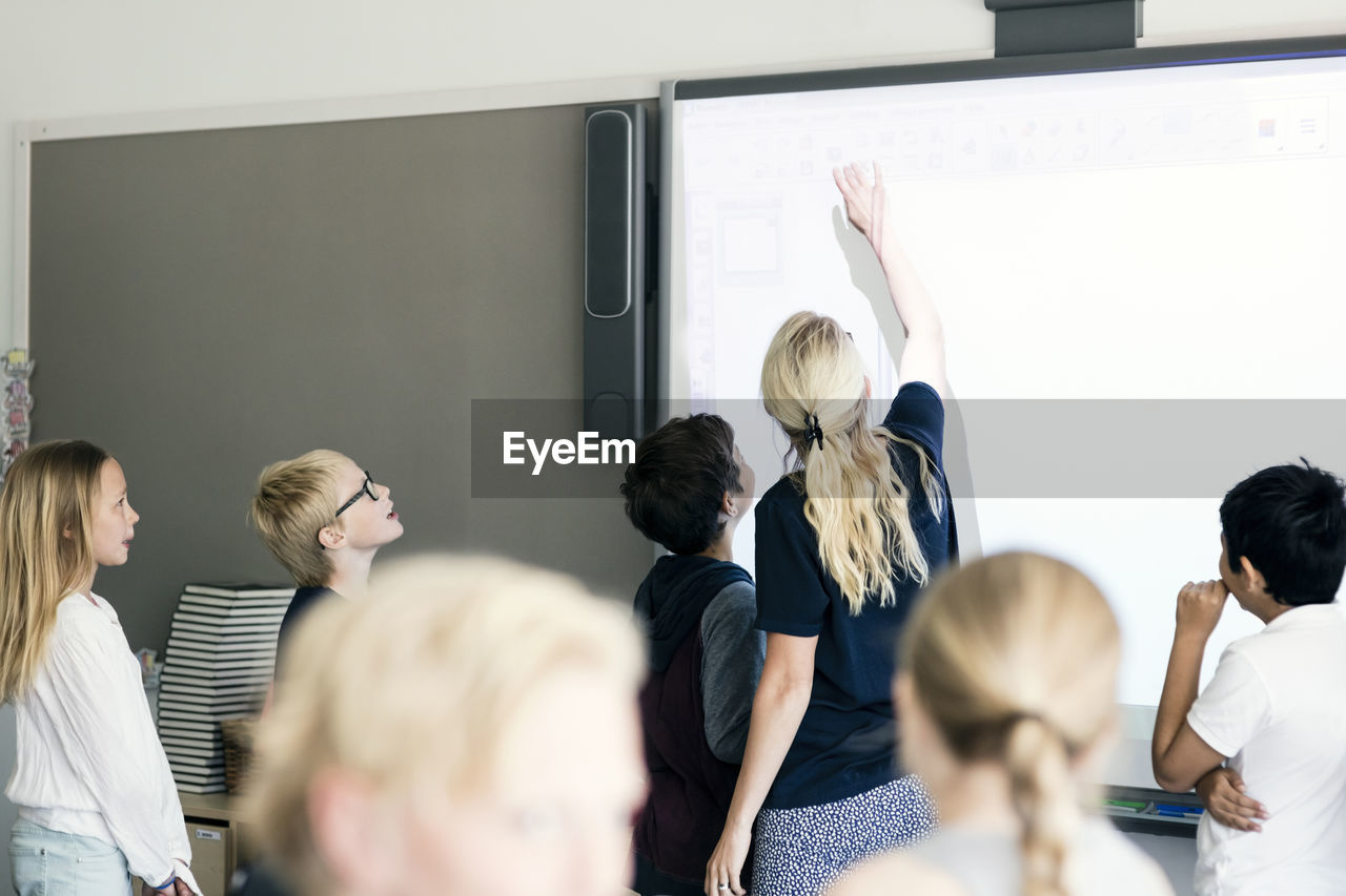 Teacher explaining students on whiteboard in classroom