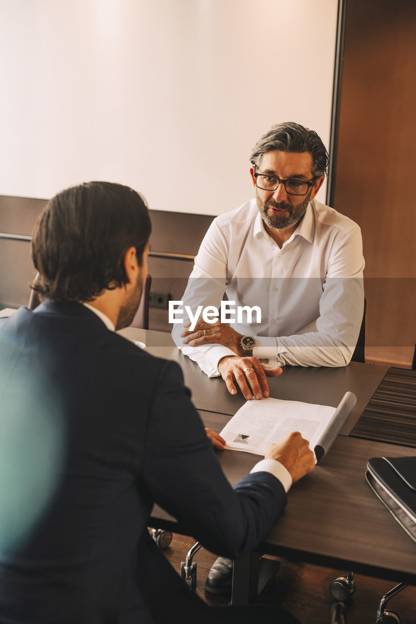 High angle view of advisor explaining document to businessman in meeting at law office