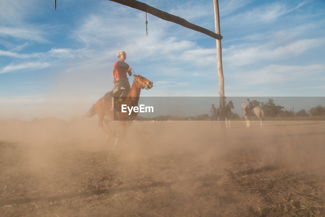 Man riding horse on landscape against sky