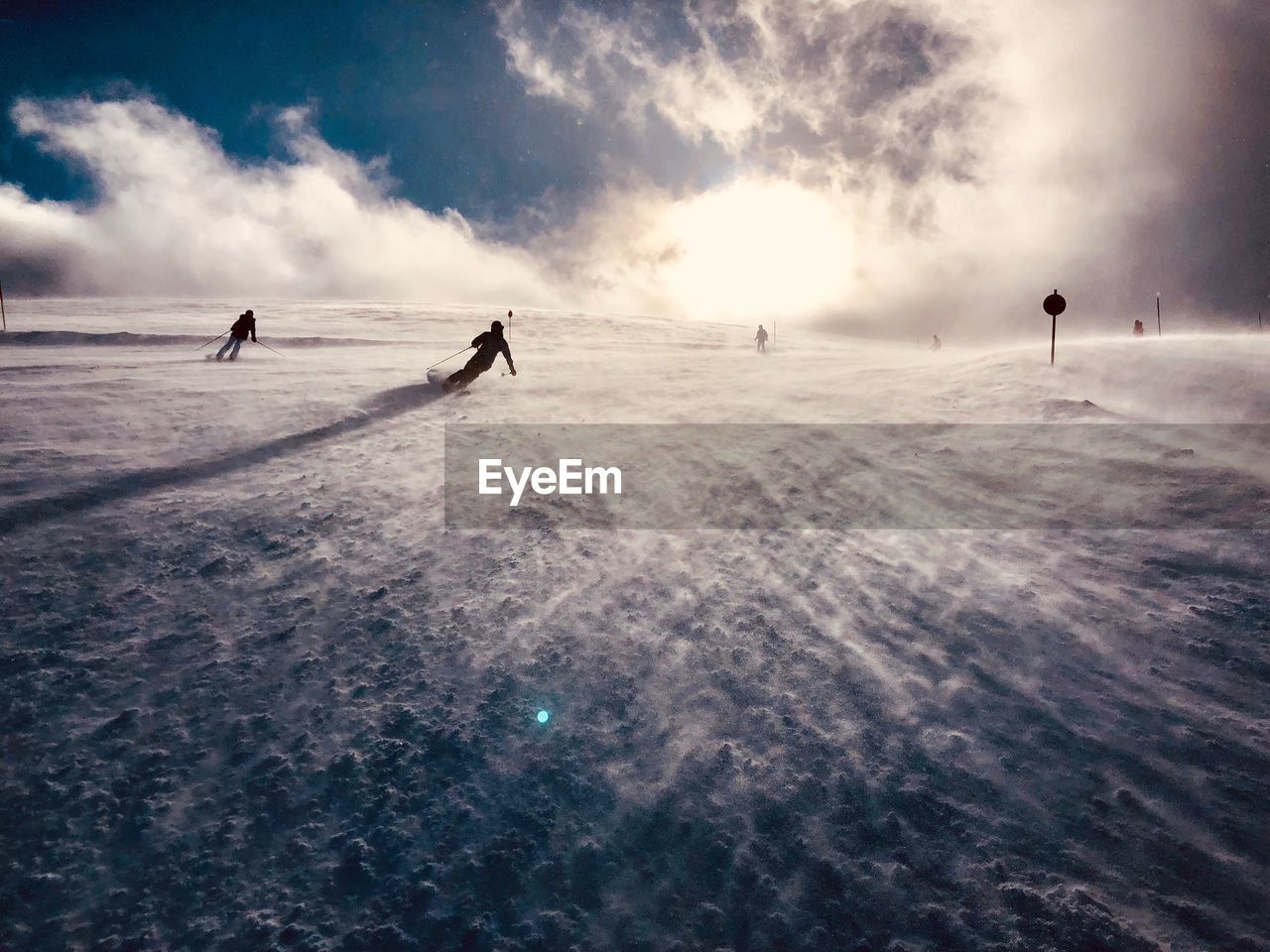 People on skiing on snow covered land against sky