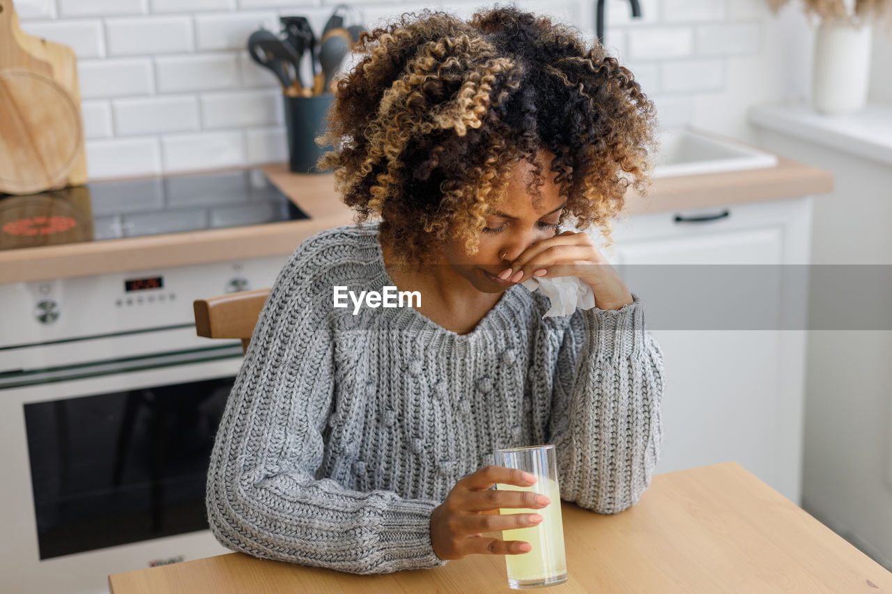 side view of young woman using mobile phone at table