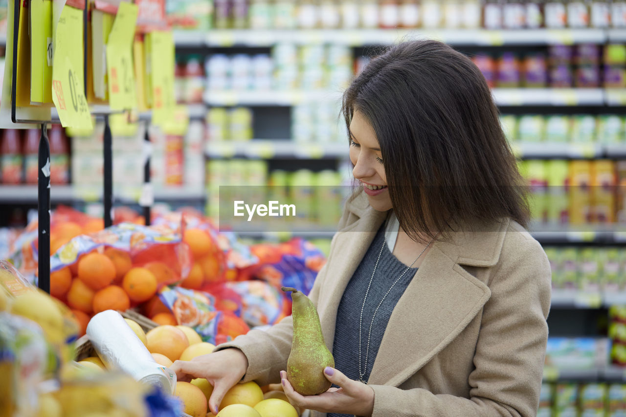 Smiling woman buying fruits at supermarket