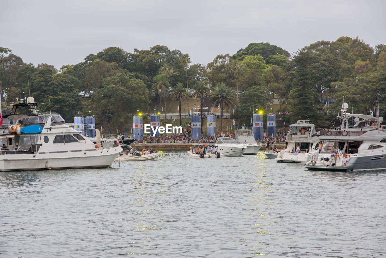 BOATS SAILING IN HARBOR AGAINST SKY