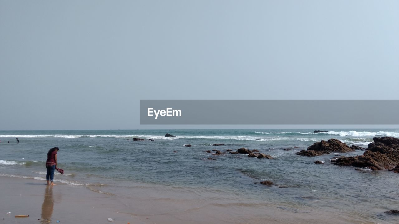 MAN ON BEACH AGAINST CLEAR SKY