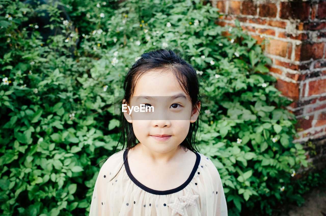 Close-up of smiling cute girl standing against plants