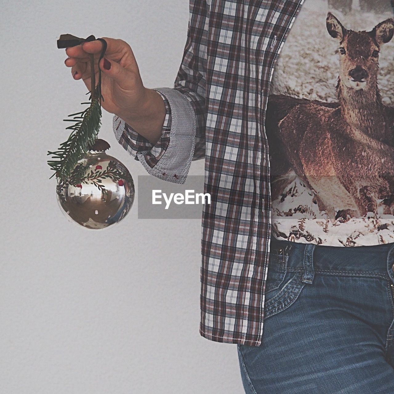 Midsection of woman holding christmas ornament on white background