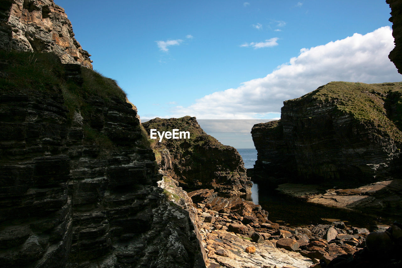 LOW ANGLE VIEW OF ROCK FORMATION AMIDST ROCKS AGAINST SKY