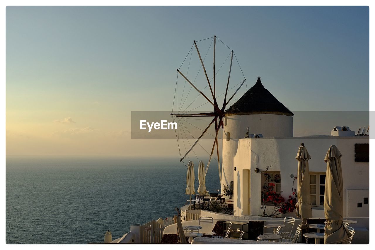 Windmill by sea against sky