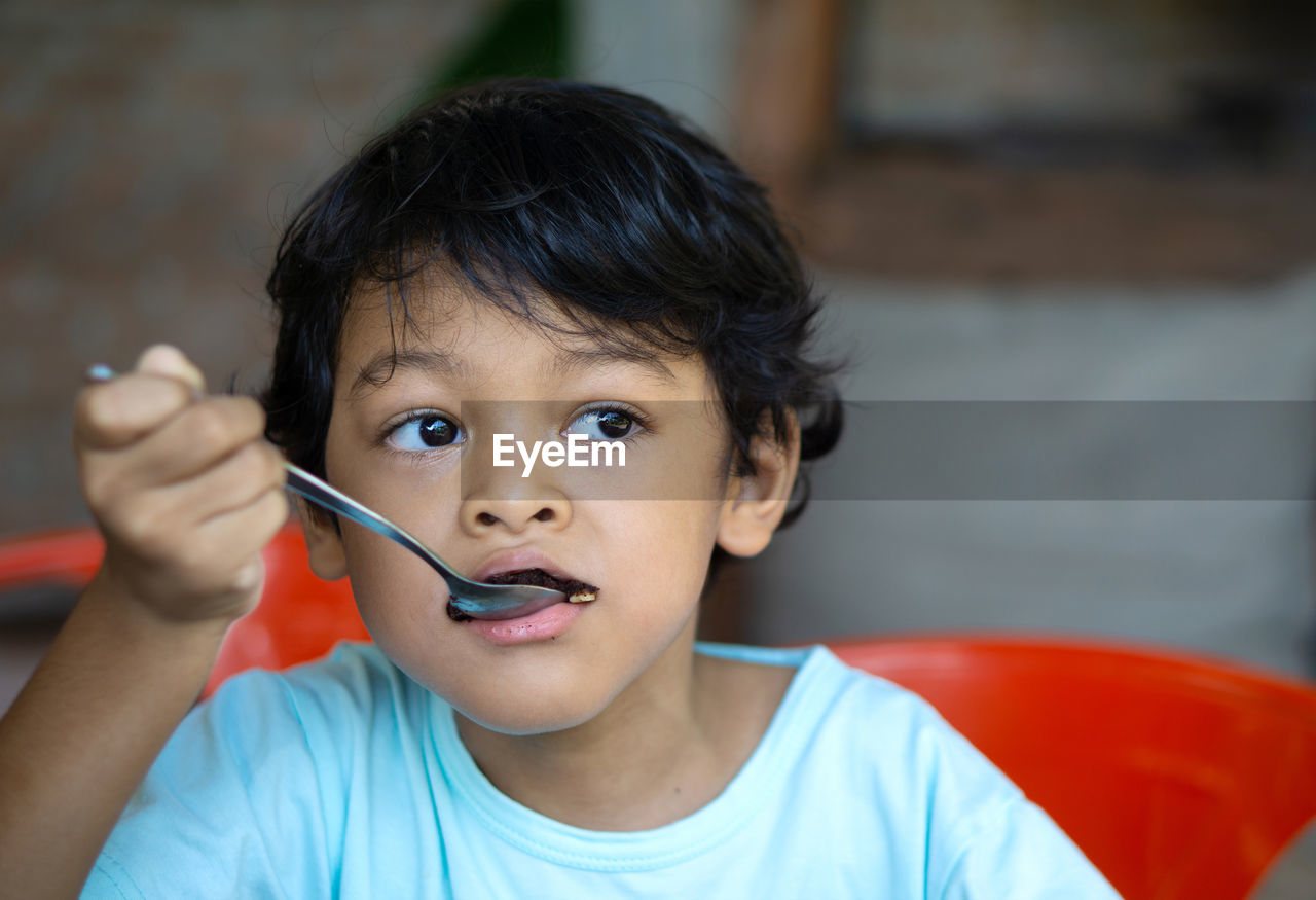 Close-up of boy eating food at home