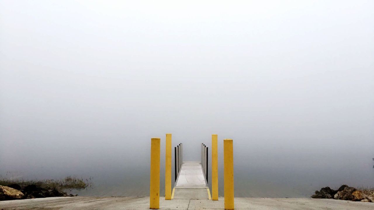 Vanishing pier leading towards lake in foggy weather