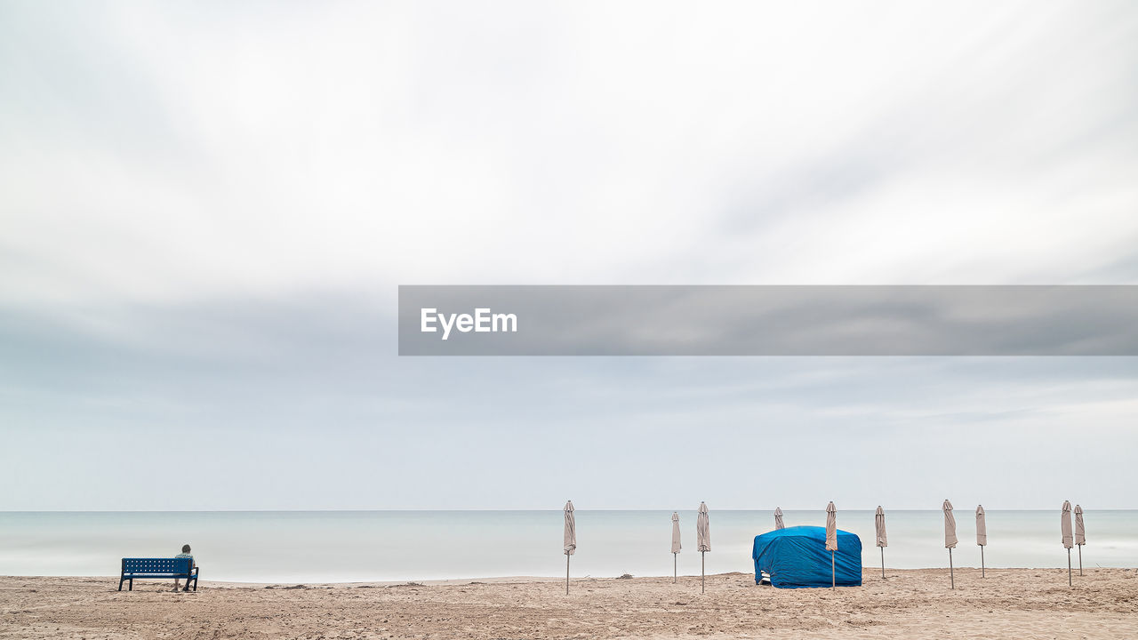 Deck chairs on beach against sky