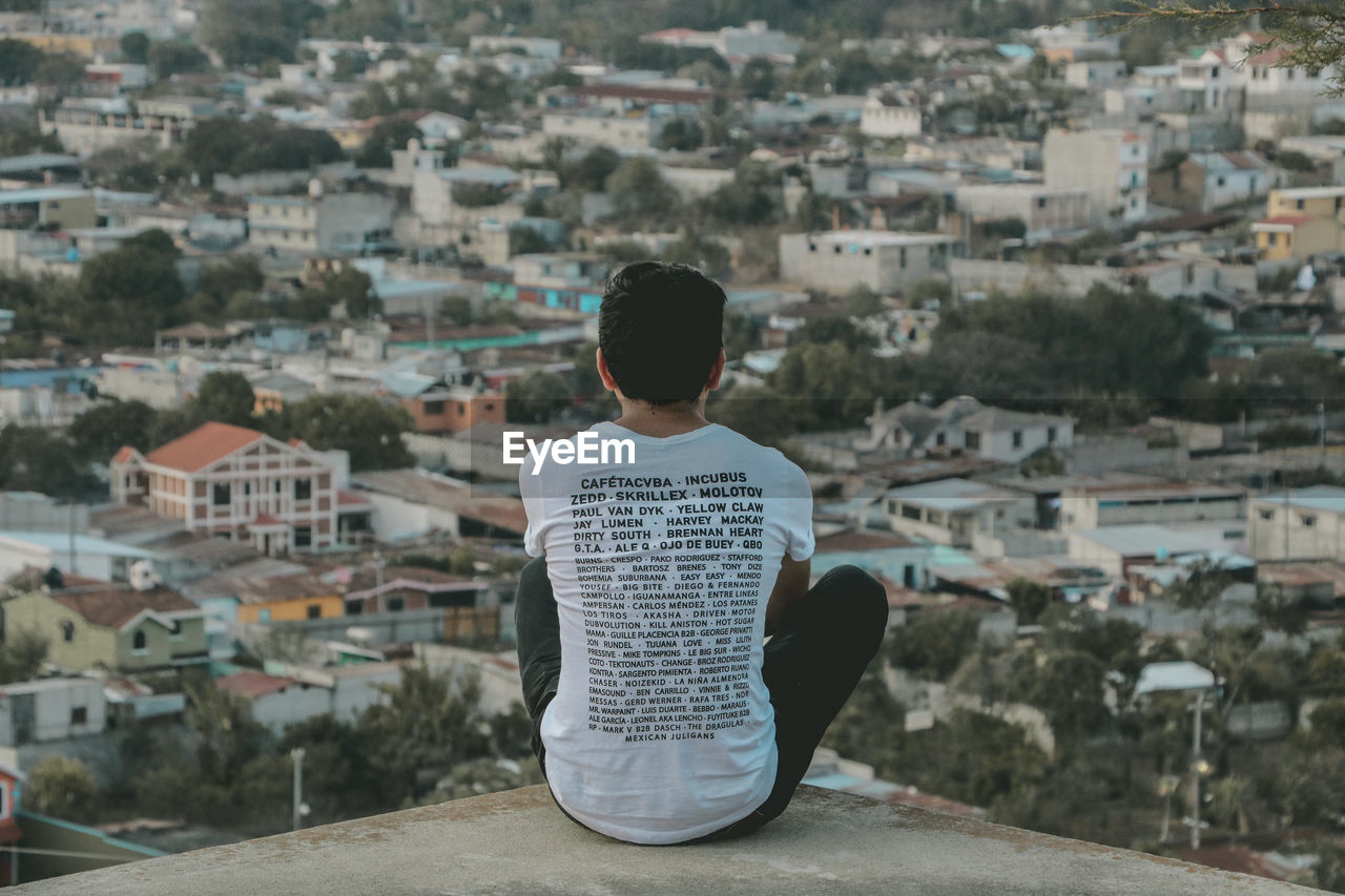 REAR VIEW OF MAN WITH CITYSCAPE IN FOREGROUND