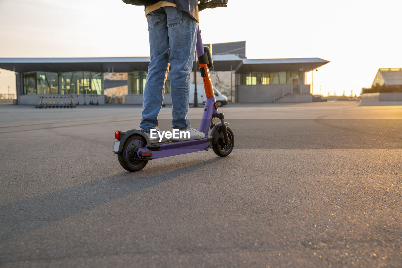 Businessman riding electric push scooter on street