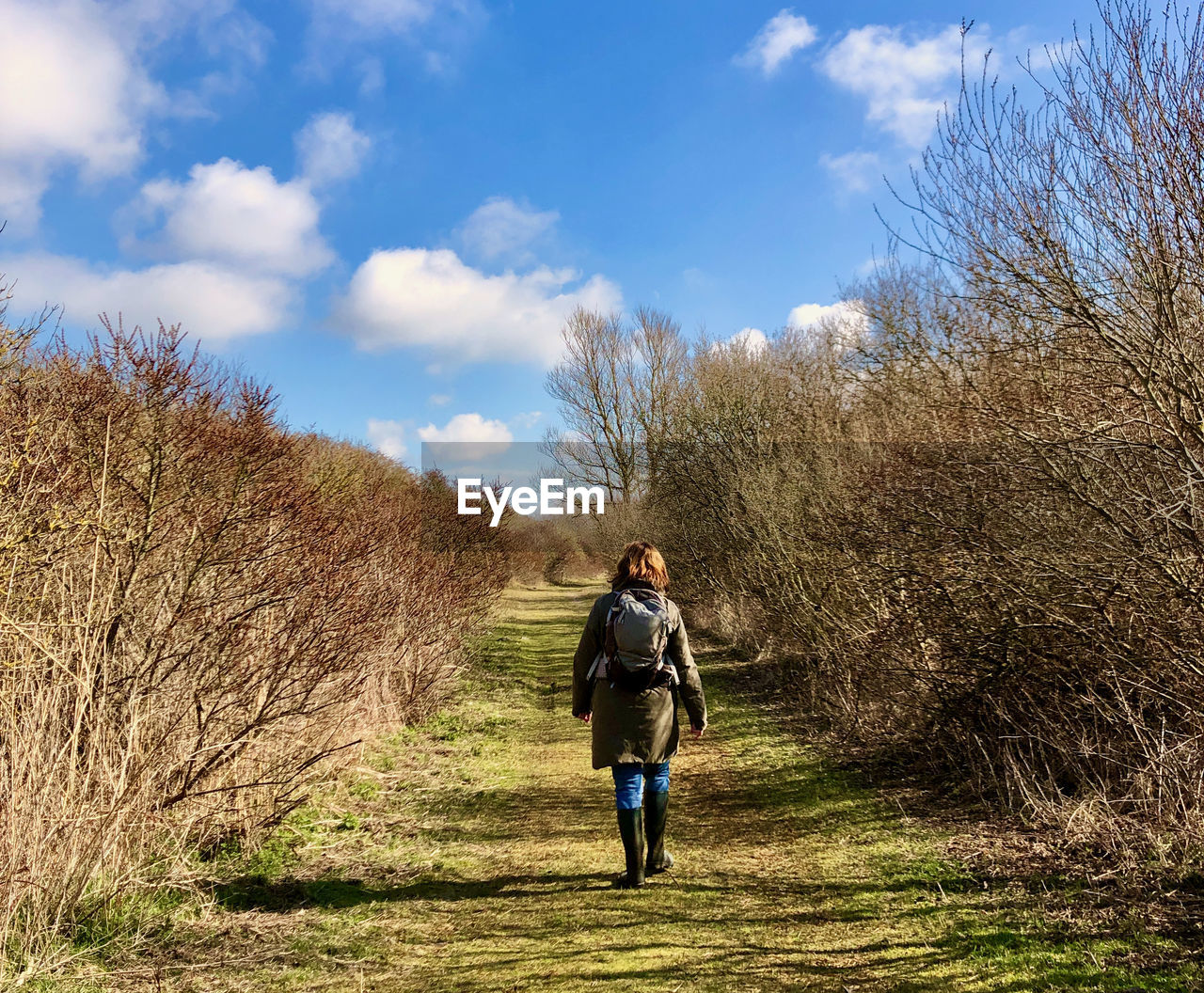 Rear view of woman walking on footpath against sky