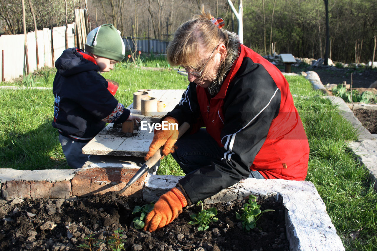 Mother and son gardening in yard