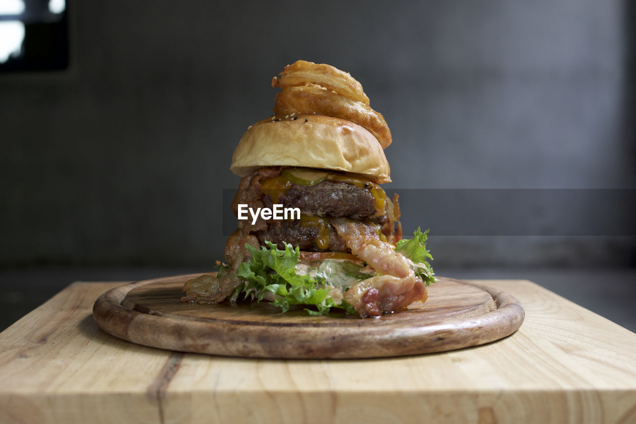 CLOSE-UP OF BURGER ON CUTTING BOARD ON TABLE