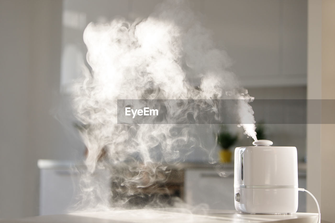 Close-up of smoke emitting from glass on table