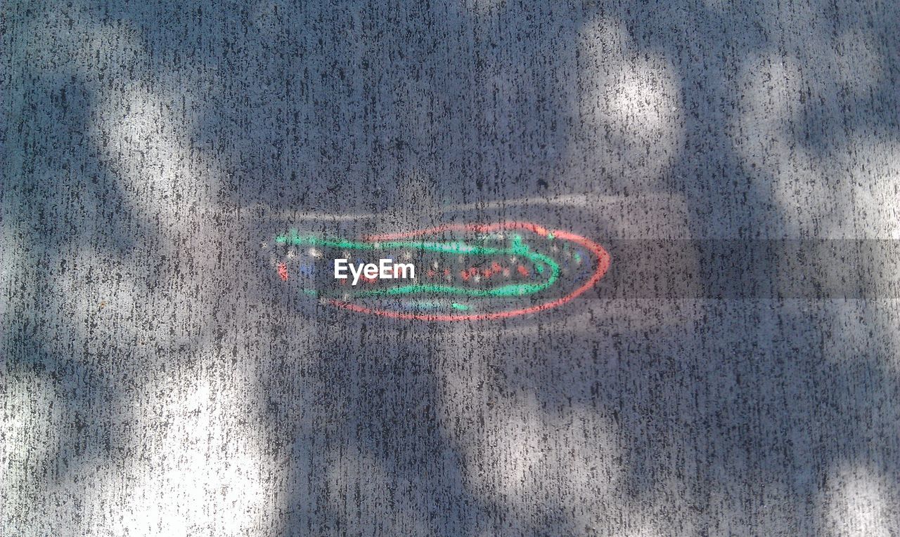 CLOSE-UP OF MULTI COLORED TEXT ON GROUND