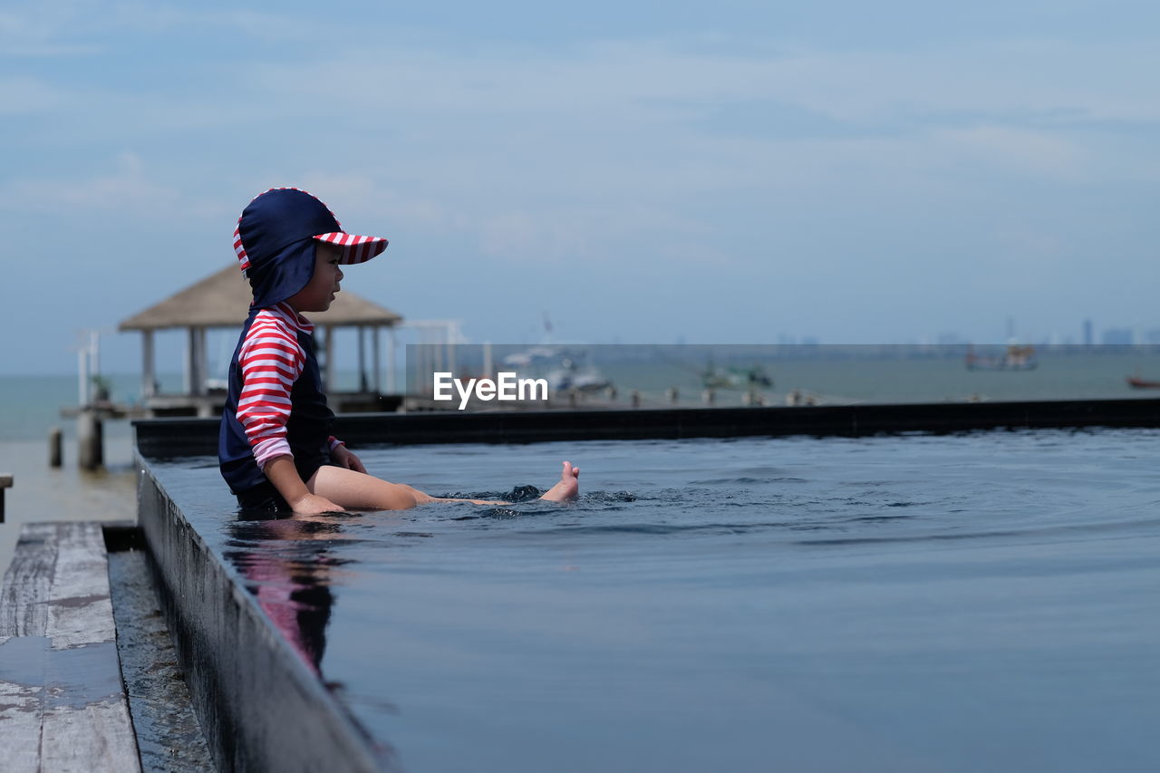 Side view of girl sitting in swimming pool