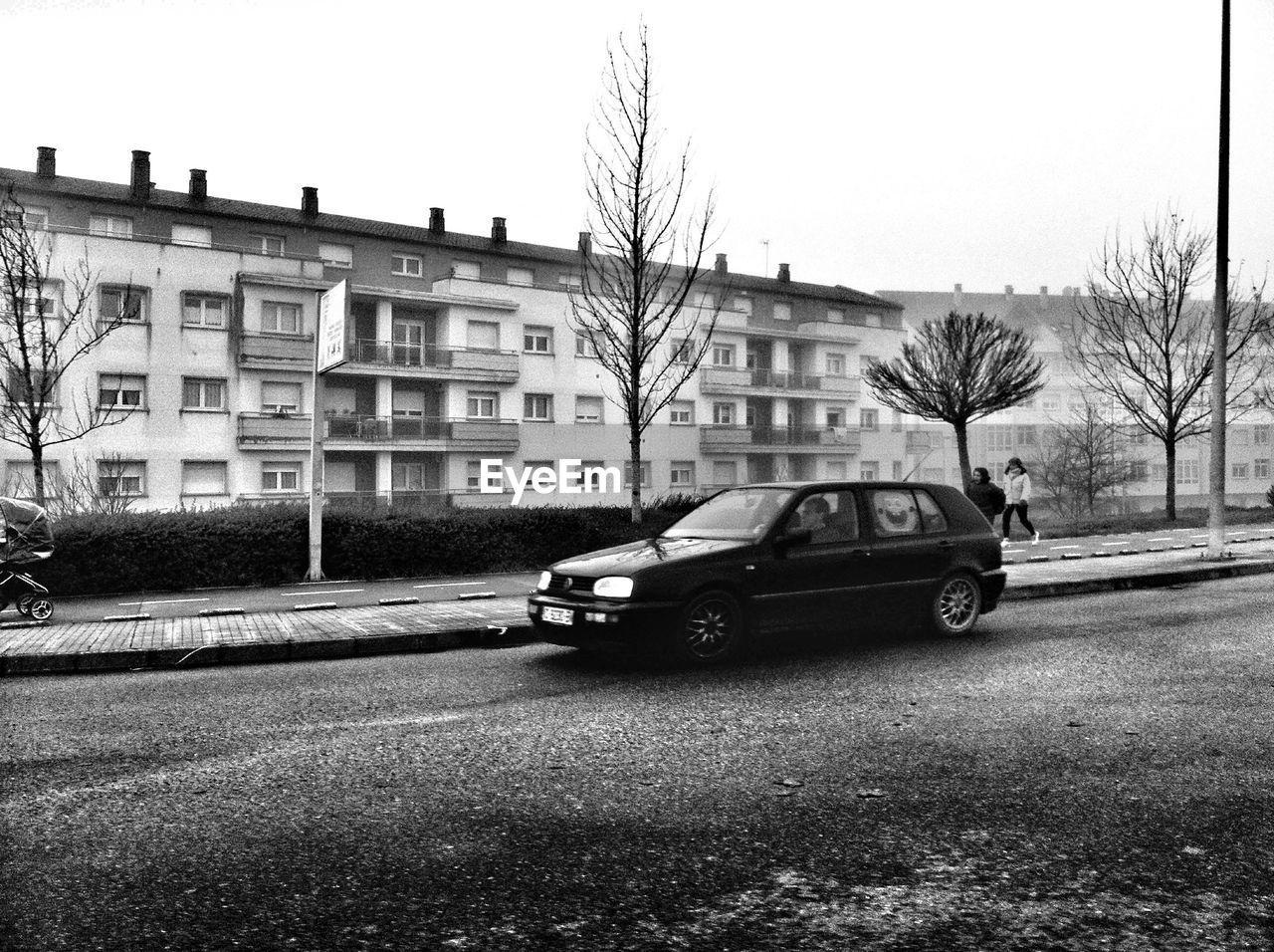 CARS ON ROAD BY BUILDINGS AGAINST SKY