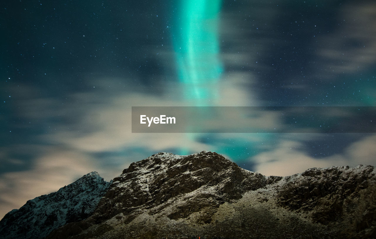 Scenic view of aurora borealis and mountains against sky at night