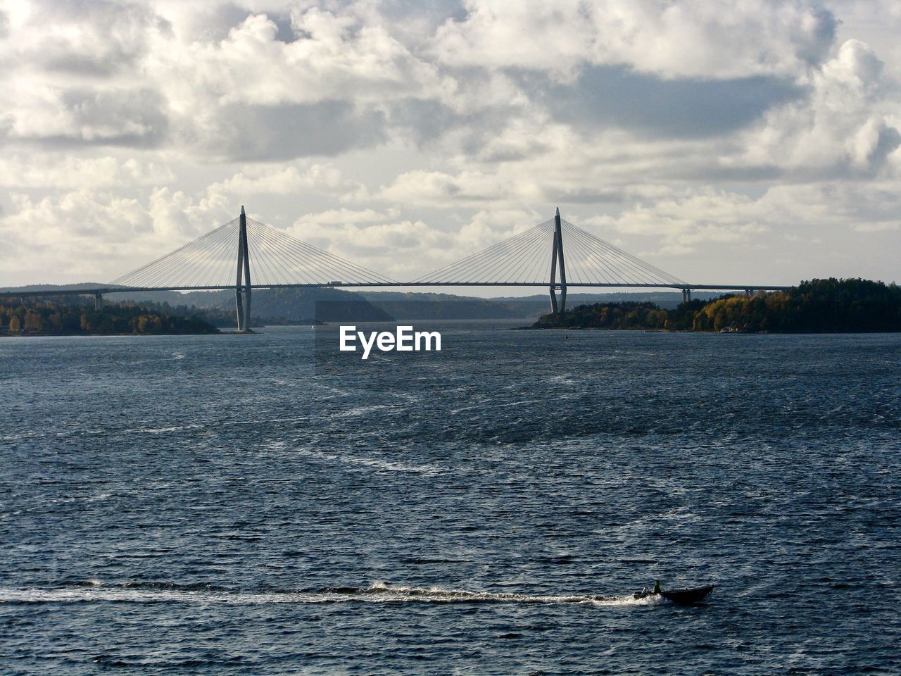 Bridge over sea against cloudy sky