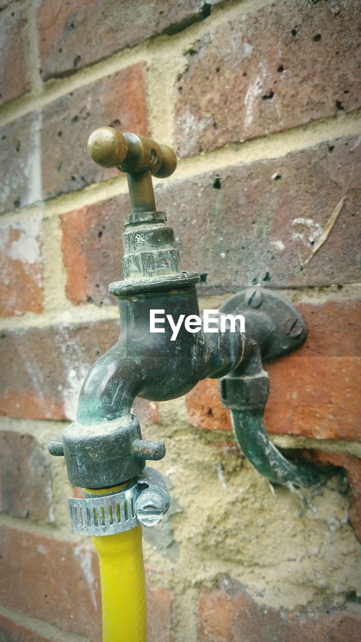 Close-up of hose attached to faucet on wall