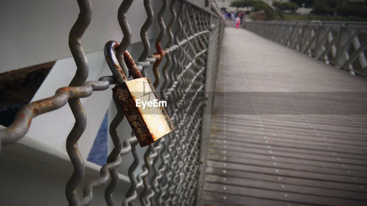 CLOSE-UP OF PADLOCKS HANGING ON FOOTBRIDGE