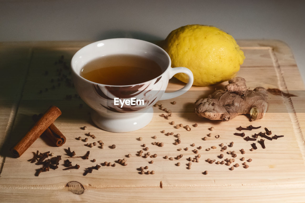 High angle view of herbal tea by spices and lemon on cutting board