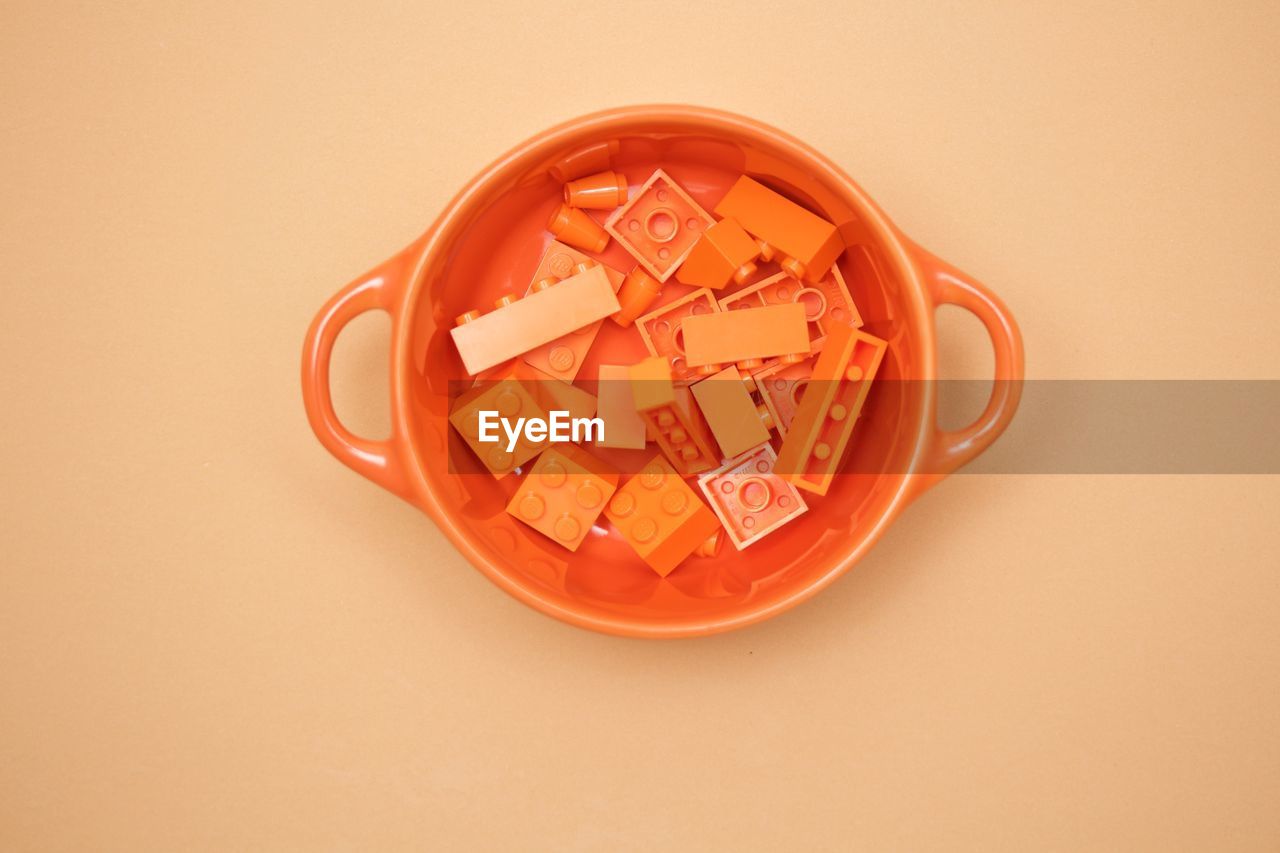 Directly above shot of toy blocks in bowl over colored background