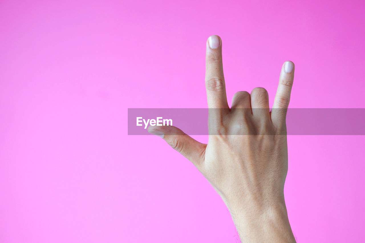 Close-up of human hand gesturing against pink background