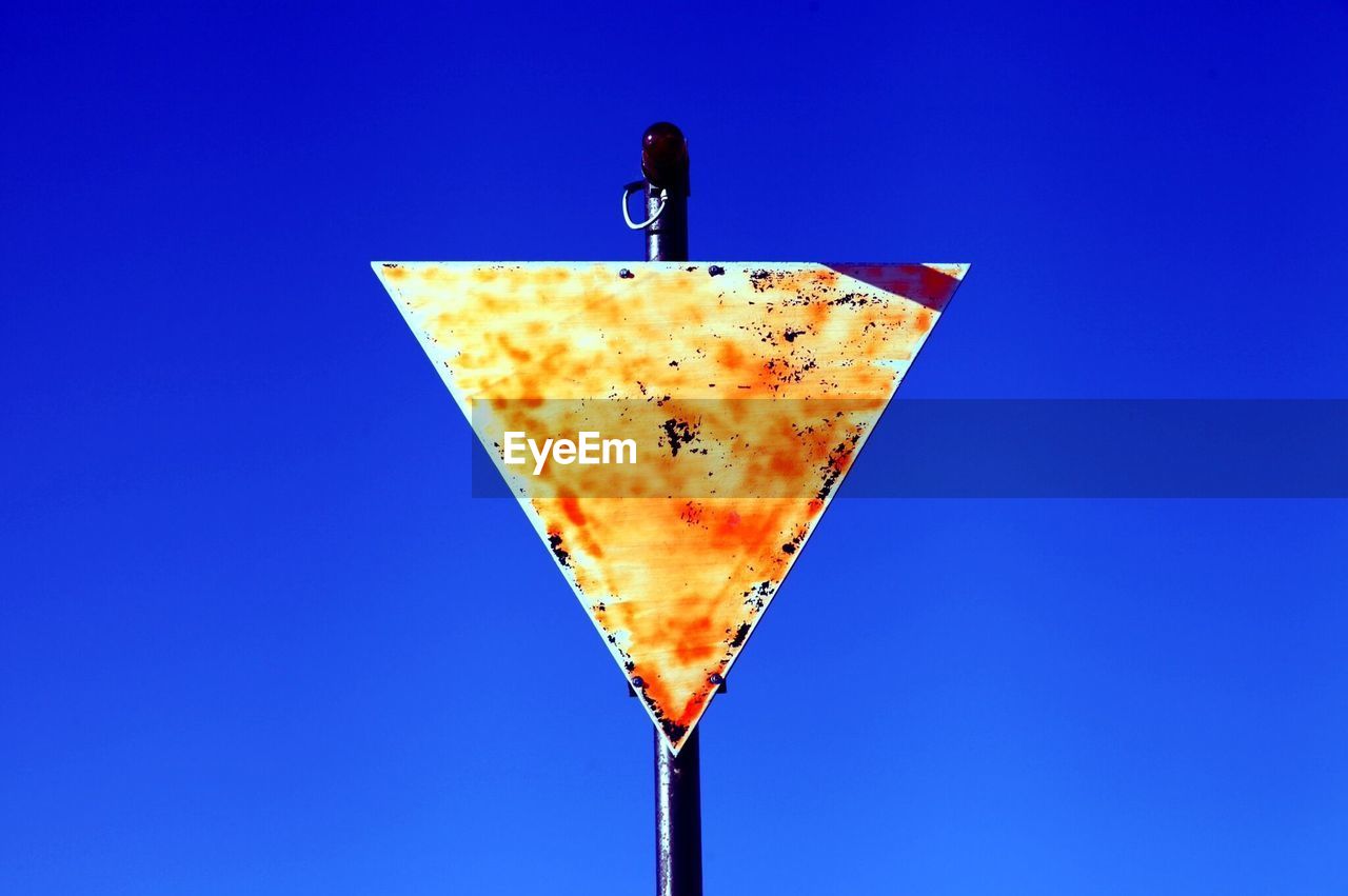 Low angle view of warning triangle against clear blue sky