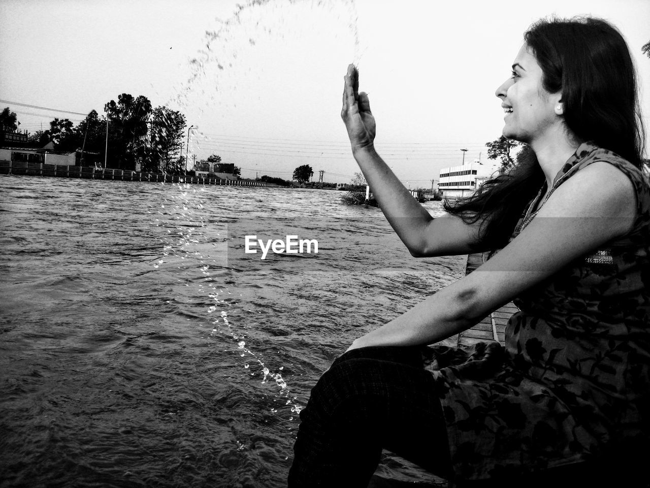 Side view of young woman sitting by river