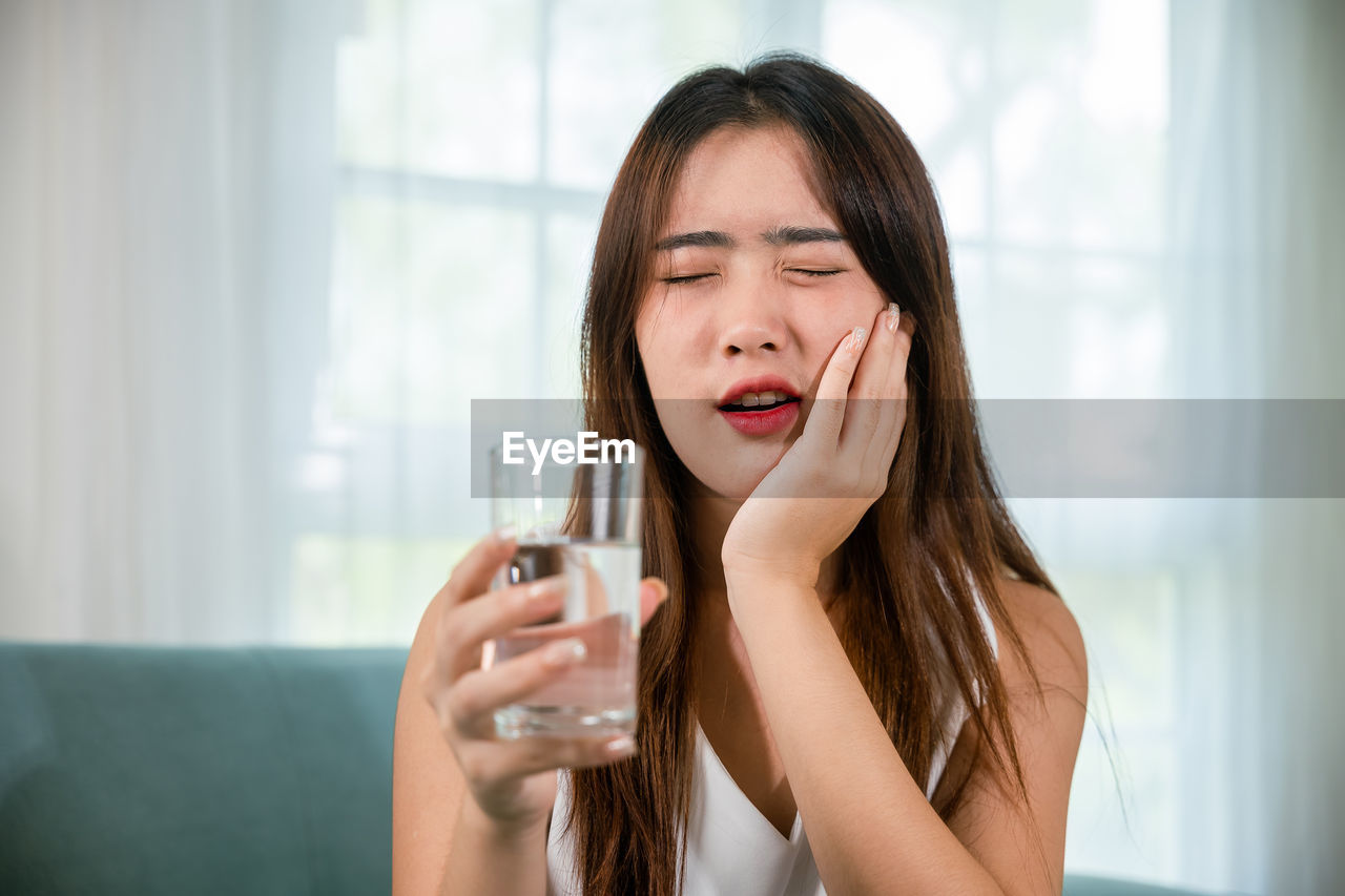 portrait of young woman drinking glass at home