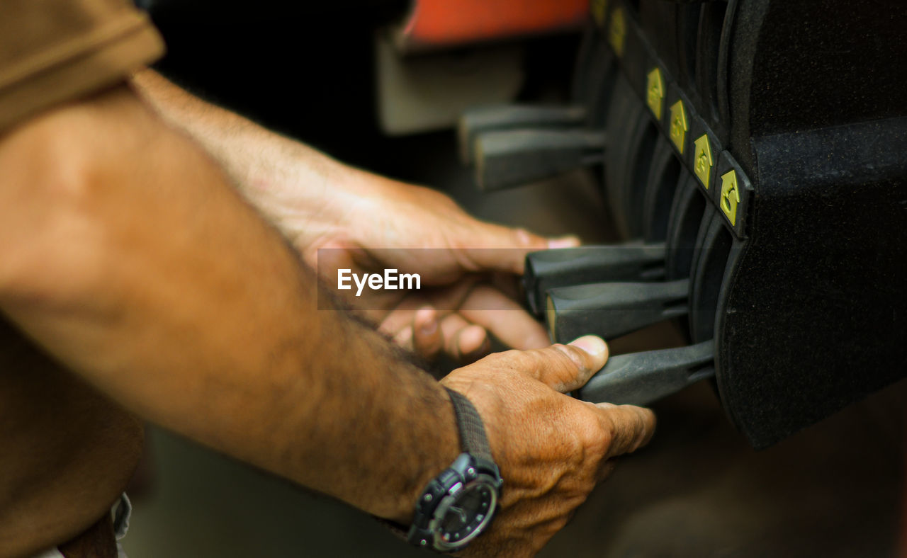 Midsection of man operating machinery in factory