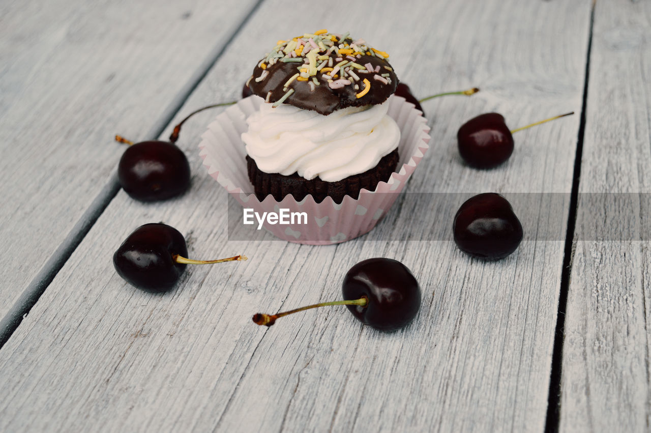 High angle view of cupcakes and cherry on table