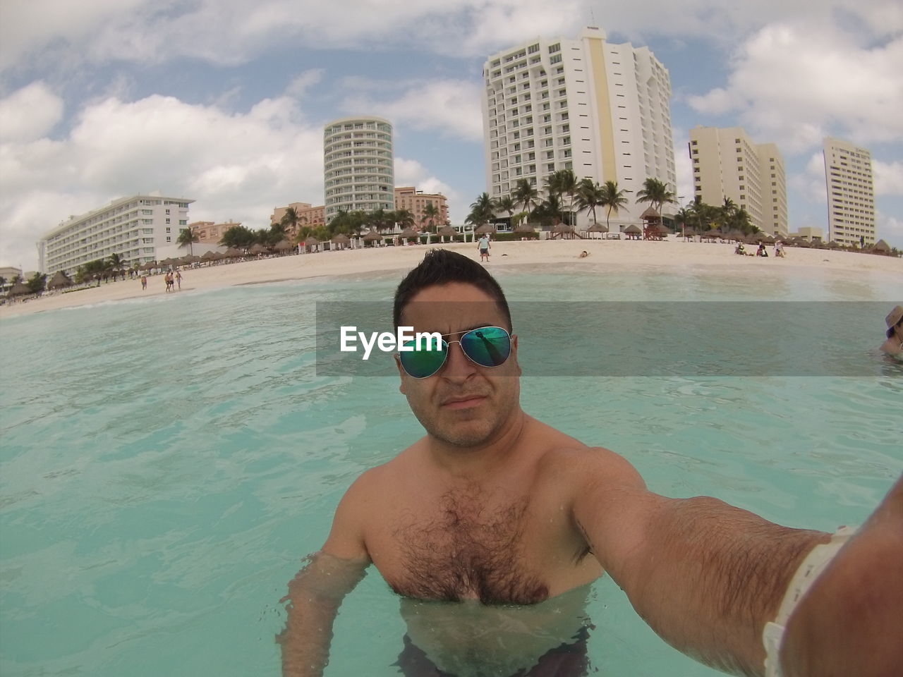 PORTRAIT OF YOUNG MAN IN SWIMMING POOL AT BEACH